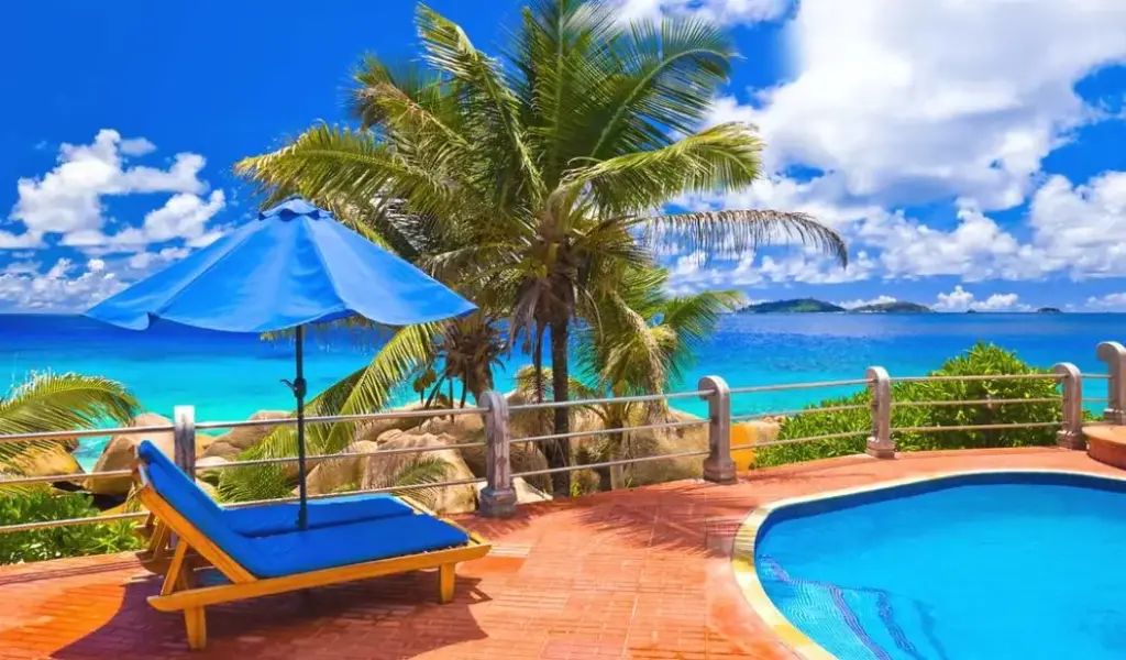 Пляж с пальмами, бирюзовым морем и зонтиком у бассейна напоминает атмосферу лучших курортов для отдыха в Египте.