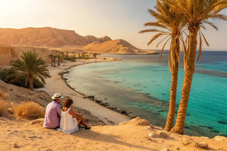 Пара, сидящая у живописной бухты с пальмами и прозрачным морем, создаёт общее представление о погоде в Египте в период осень.