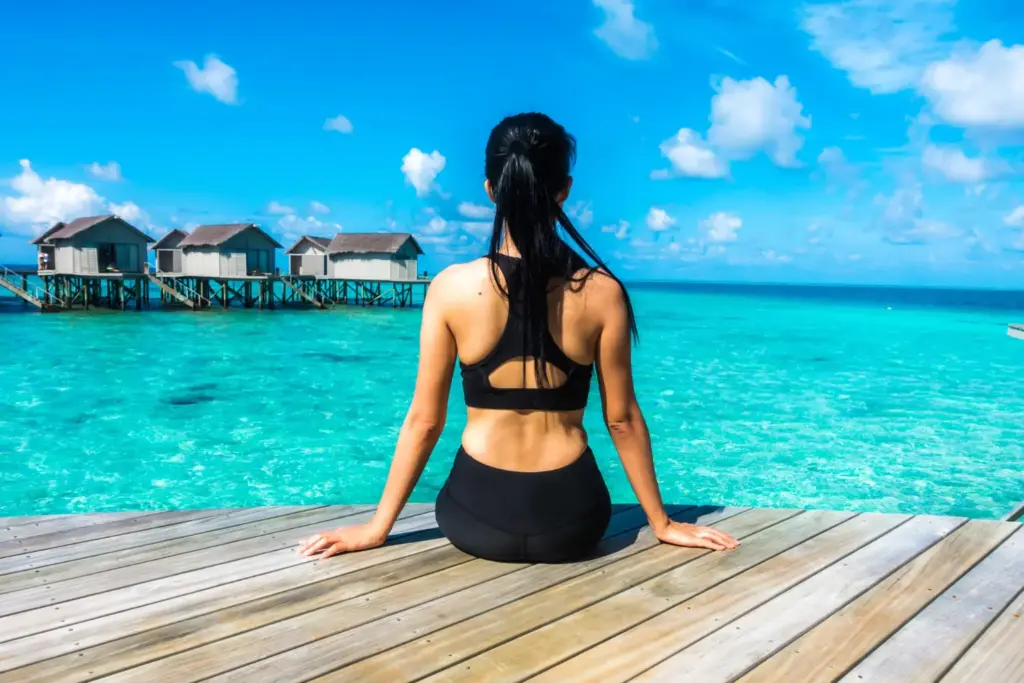 Когда ехать на Мальдивы: девушка на фоне прозрачной бирюзовой воды и солнечной погоды, характерной для тёплого климата островов