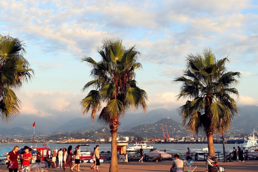 Багаж и ручная клад на рейсах туроператоров: набережная с пальмами, туристами и видом на море и горы