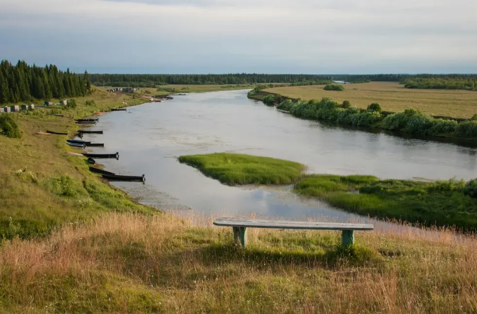 Как меньше устать в путешествии и увидеть больше: сколько экскурсий брать на день — спокойная река с зелёными островками, лодки у берега и лавочка на холме.