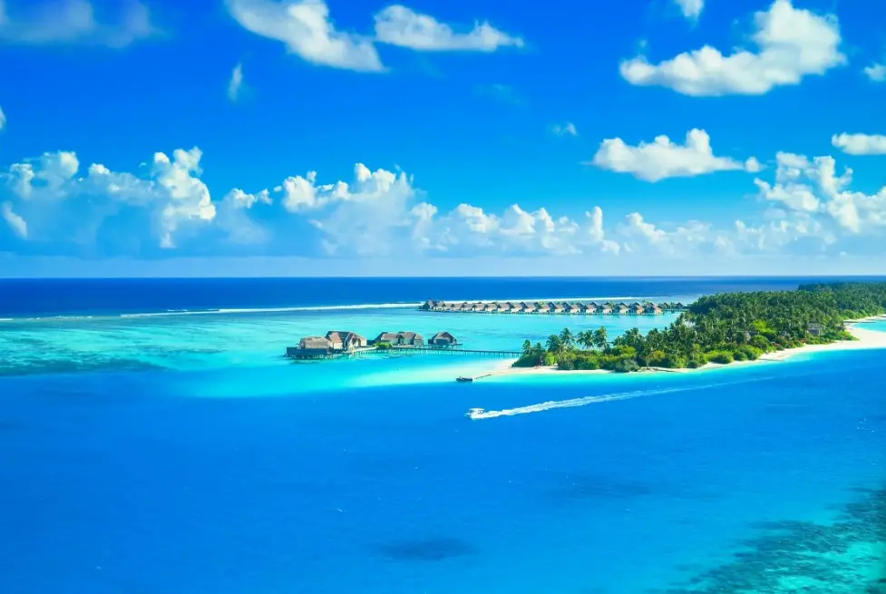 Как не переплатить за тур — вид с воздуха на тропический остров с бирюзовой лагуной и бунгало на воде (overwater villas)