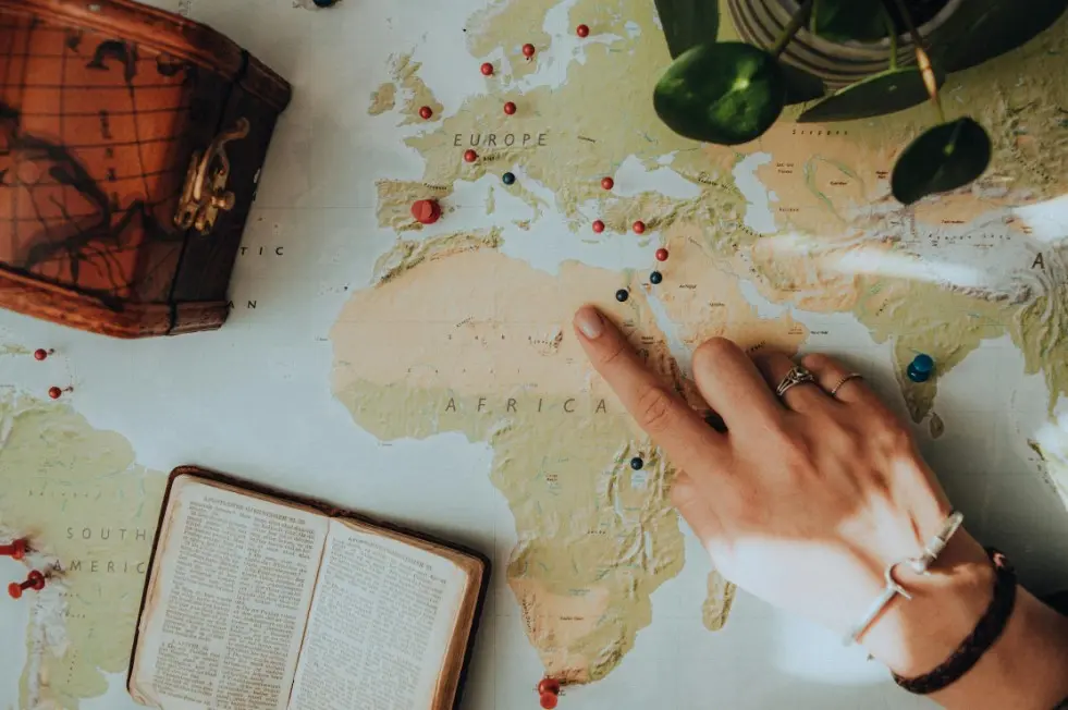 Как выбрать гида — рука указывает на карту мира с отмеченными маршрутами и точками путешествия