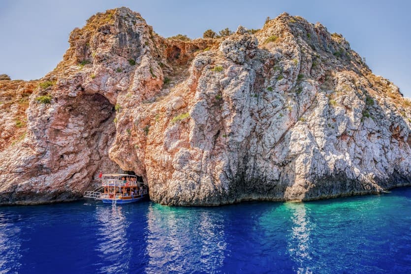 Как выбрать тур с удобным временем вылета — морская бухта у скал, лодка у пещеры и прозрачная вода