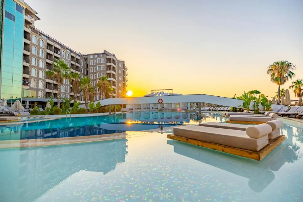 Квартиры и апартаменты или отель: что выбрать для тура — бассейн в современном отеле на закате, шезлонги и пальмы
