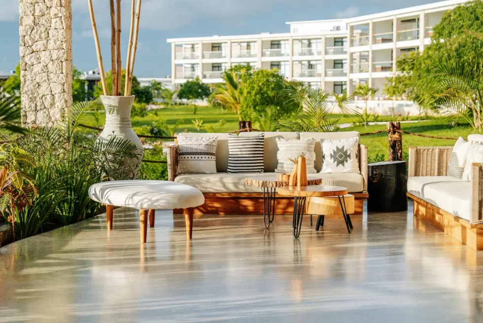 Квартиры и апартаменты или отель: что выбрать для тура — терраса апарт-отеля с зоной отдыха, диванами и видом на зелёную территорию