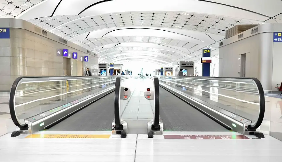 Ночные вылеты и ранние прилёты: как это влияет на отдых — траволатор в светлом терминале аэропорта и указатели выходов на посадку