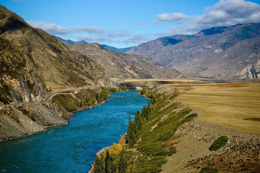 Ошибки при выборе экскурсии: горная река в долине между скалами и степными берегами на фоне хребта и облачного неба