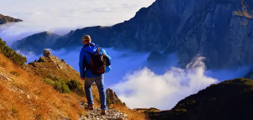 Самые интересные однодневные экскурсии в России: турист на горной тропе над облаками