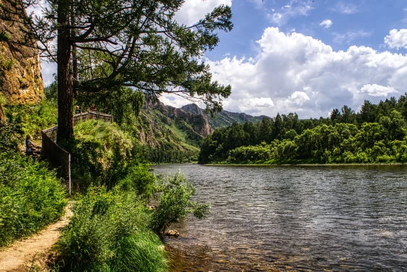 Сколько стоят экскурсии в России: живописная река у скалистого берега и леса в солнечный день