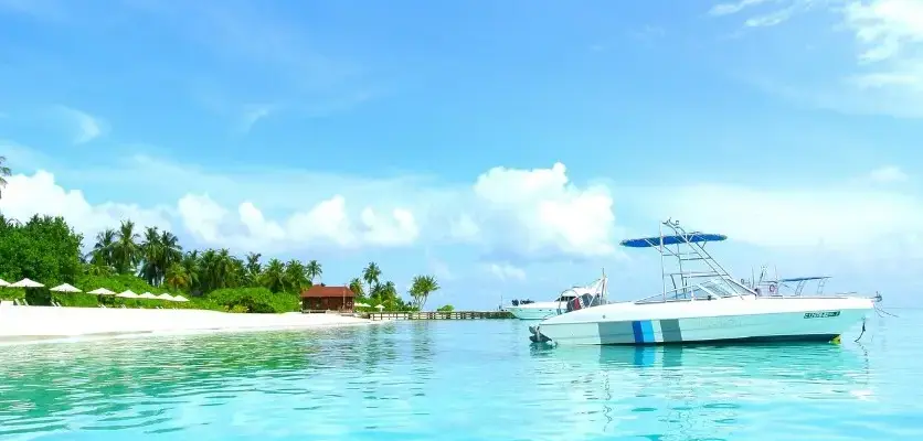 Страховка от невыезда: когда нужна и как работает — бирюзовая лагуна и белый пляж с лодкой у берега.