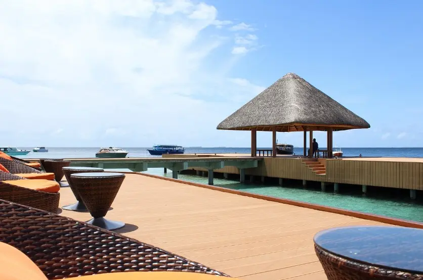 Страховка от невыезда: когда нужна и как работает — терраса у моря с пирсом и беседкой над водой на курорте.
