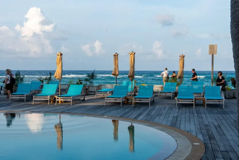 Страховка от невыезда: когда нужна и как работает — шезлонги у бассейна на фоне моря, отдых в отеле у пляжа.