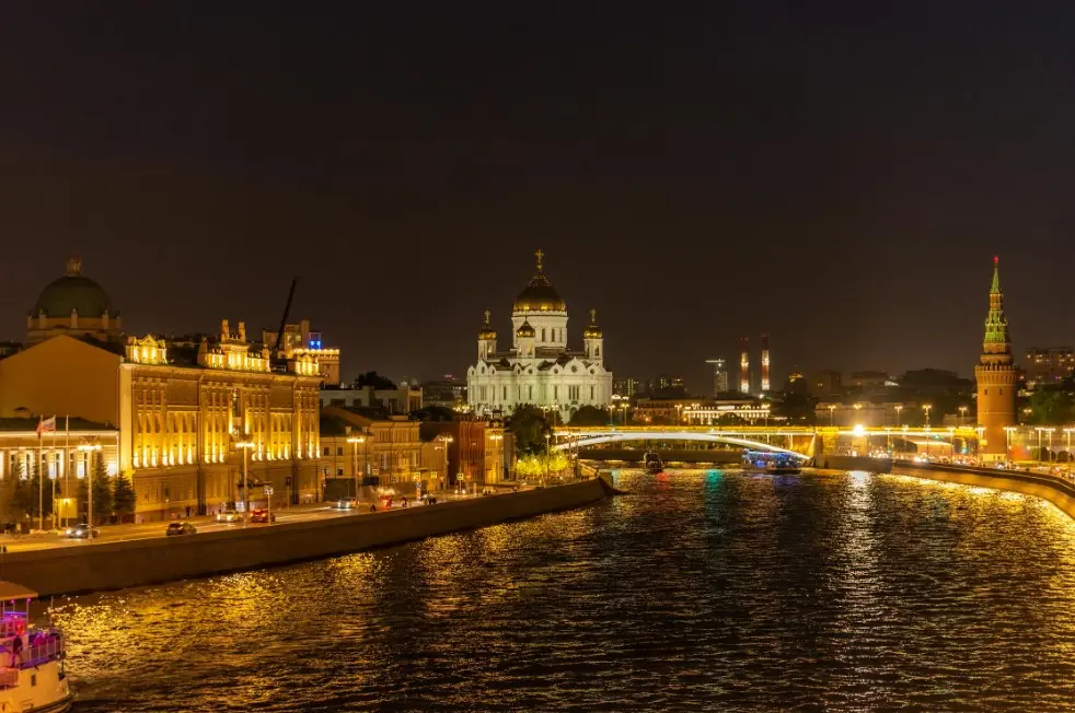 Топ 10 вечерних и ночных экскурсий в Москве — ночной вид на Москву-реку с подсветкой набережных, Храмом Христа Спасителя и кремлёвской башней вдали.