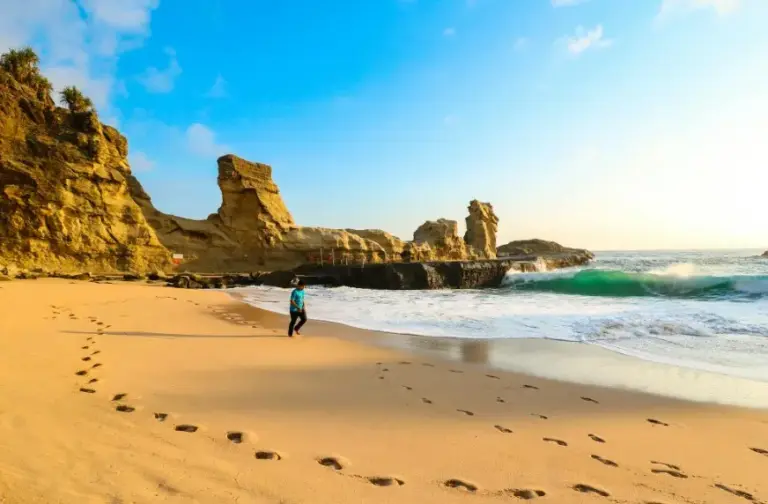 Туры покупать заранее или в последний момент — пляж на закате с песком, скалами и следами на берегу