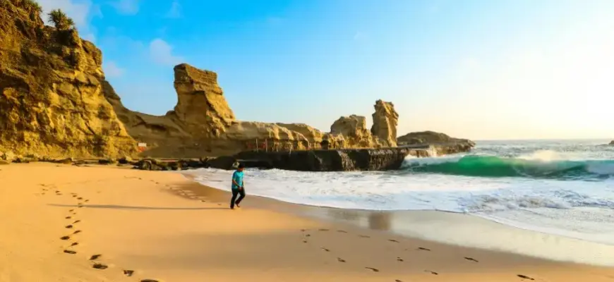 Туры покупать заранее или в последний момент — пляж на закате с песком, скалами и следами на берегу