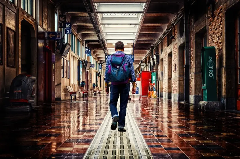 Туры с перелётом через другой город — путешественник с рюкзаком идёт по залу вокзала во время пересадки