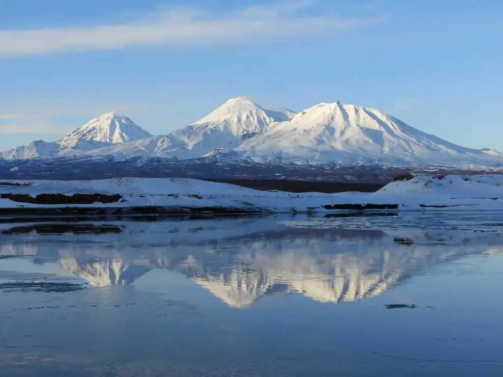 Вулканы Камчатки с заснеженными вершинами и отражением в воде
